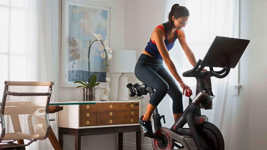 A woman in workout outfit riding Pelaton bike