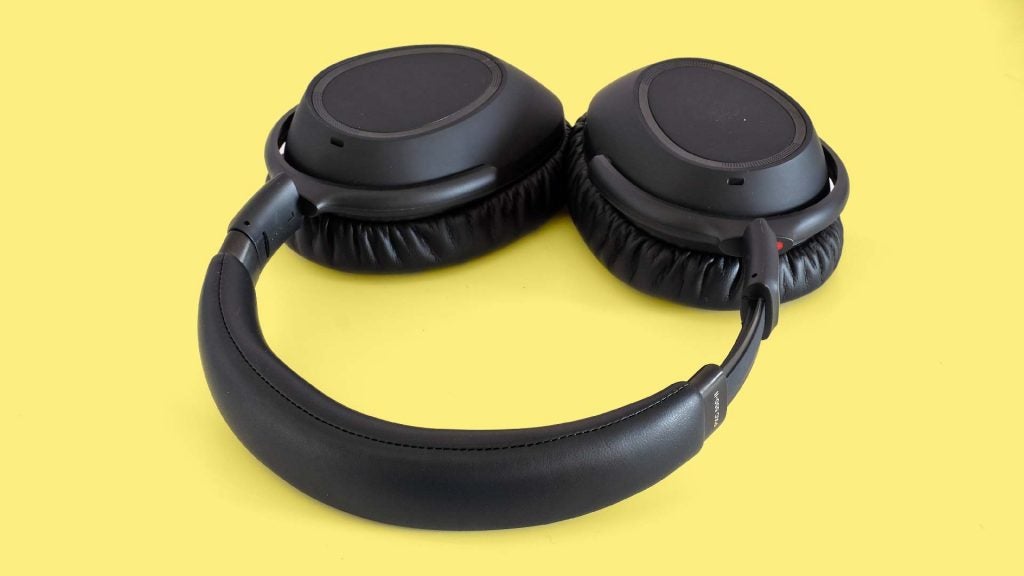A picture of black headphones kept on a yellow background