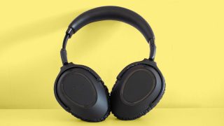 A picture of black headphones standing on a yellow background