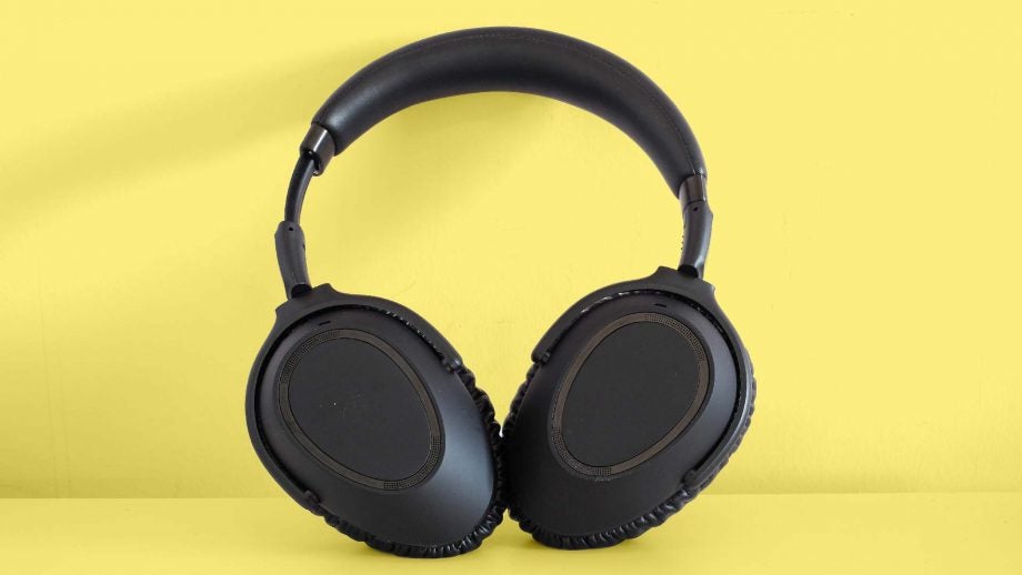 A picture of black headphones standing on a yellow background