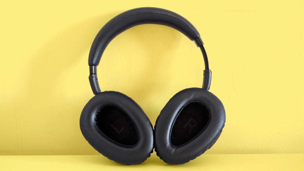 A picture of black headphones standing on a yellow background, earcups inside view