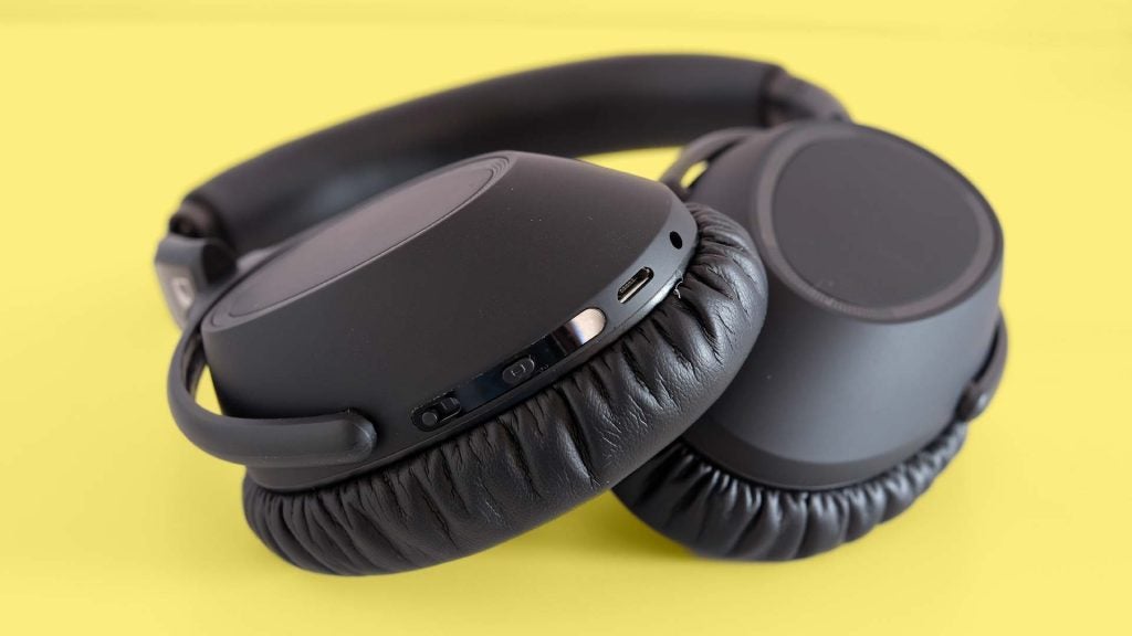 Close up image of black headphone's earcups kept on a yellow background