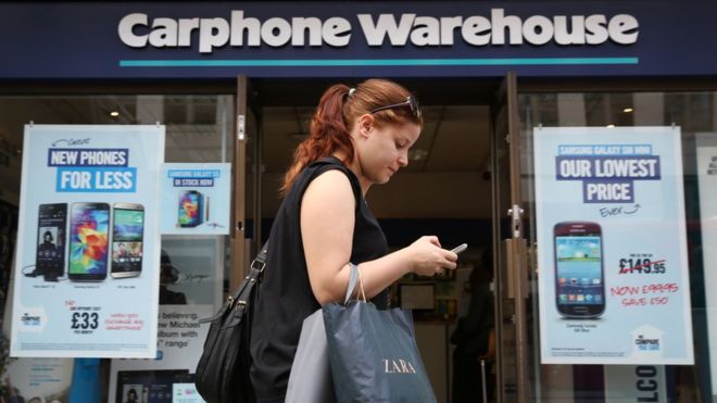 A picture of a woman walking past in front of a shop named Carphone Warehouse