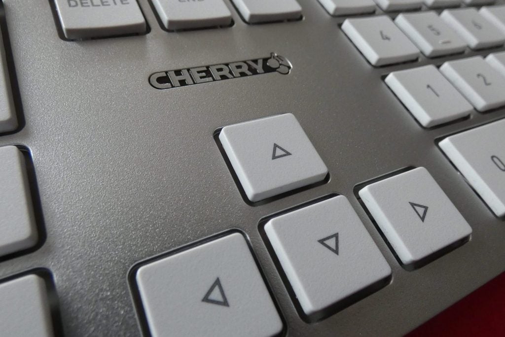 Side view of a silver DW 9000 mouse kept on a tableClose up image of DW 9000 Cherry keyboard's arrow key section