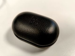 Picture of a black BO earbud's case standing on a white table