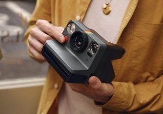 A gray-black Polaroid camera held in hand
