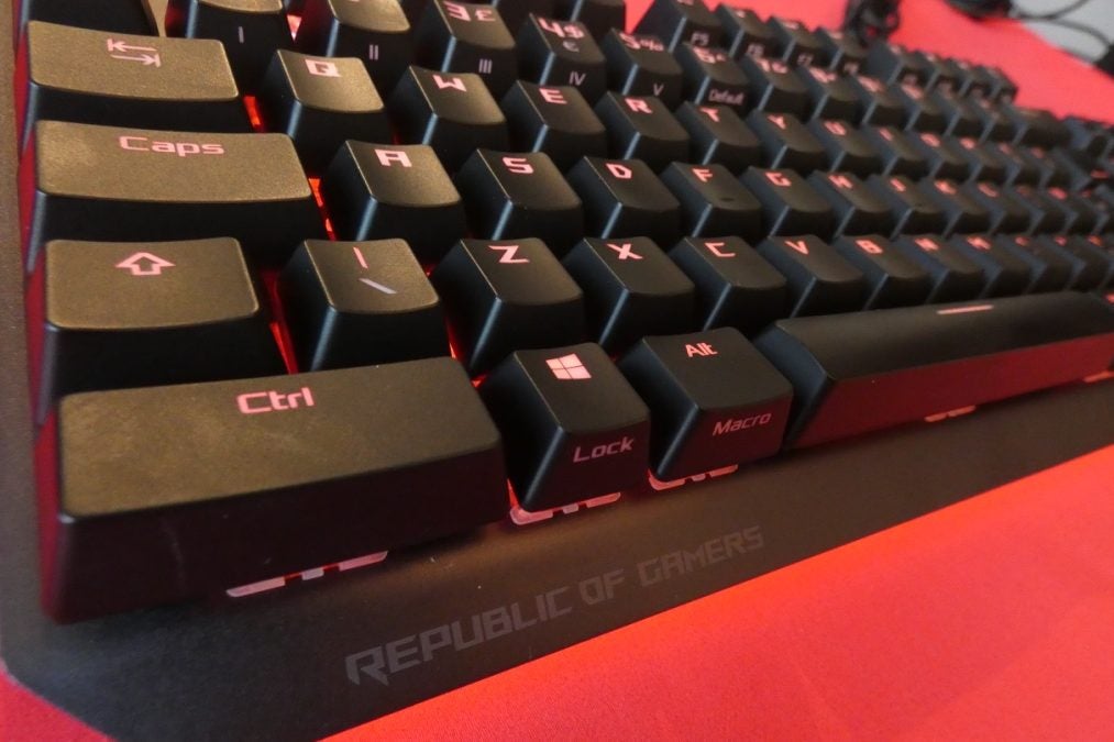 Picture of left bottom part of a black ROG Strix Scope TKL Deluxe keyboard with red lights beneath the keys