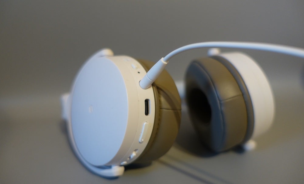 Close up image of white Sennheiser HD 450BT headphones with an audio cable connected