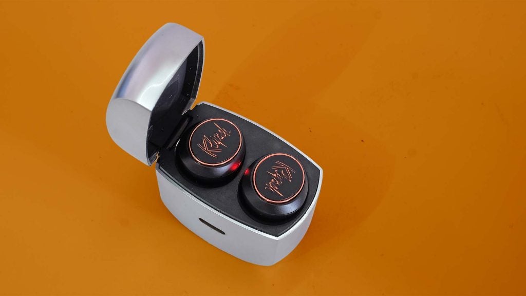 Black Klipsch earbuds resting in its case standing on a table, view from top