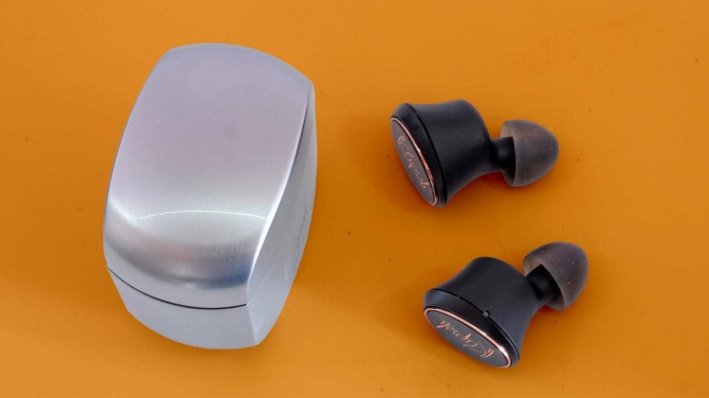 Black Klipsch earbuds kept on a table with its case standing beside, view from top