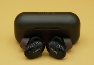 Black 1More ANC earbuds kept beside it's case on a table