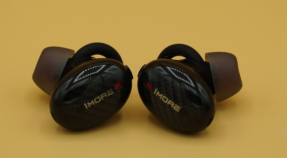 Close up image of black 1More ANC earbuds kept on a table