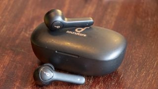 Black Anker Soundcore Life P2 earbuds kept on it's case on a wooden table