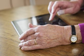 An old lady using a black tablet kept on a table