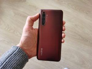 Back panel view of a chocolate brown Realme smartphone held in hand
