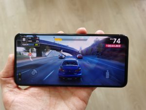 A black smartphone held in hand displaying a picture of car racing game