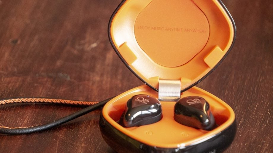 Black Shanling MTW100 earbuds resting in it's case on a table
