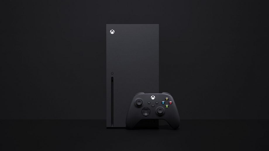 A black Xbox with it's controllers standing on a black background