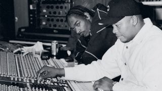 A black and white picture of Dr. Dre working on music controls