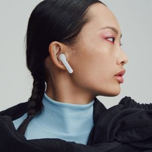 A woman in black outifit wearing white Urbanears Alby earbuds