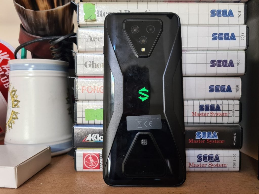 A Black Shark 3 smartphone standing against a tower of books facing back, back panel view