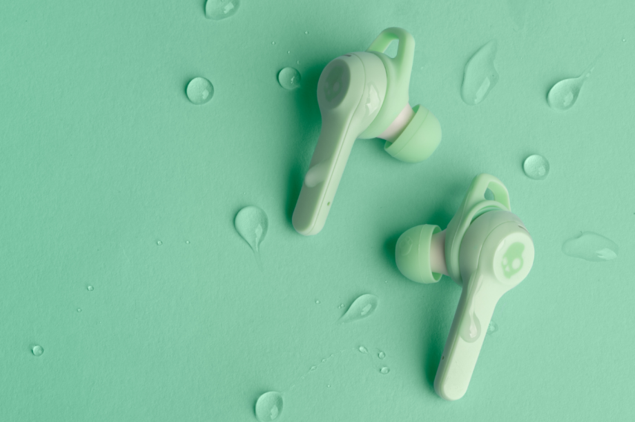Green-white Skullcandy Indy Evo earbuds resting on a mind background