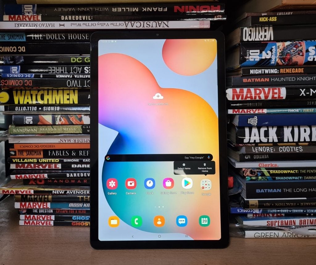 A black Galaxy Tab S6 lite standing against a tower of books displaying homescreen