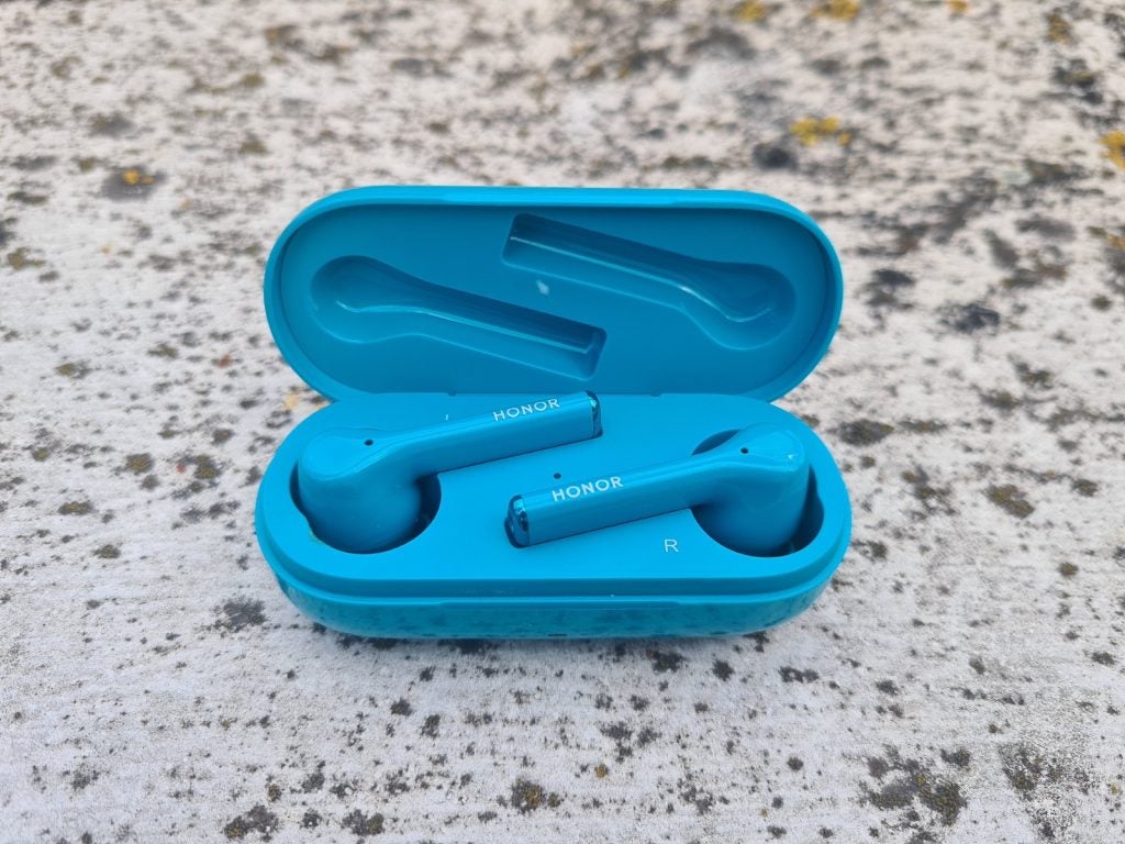 Blue Honor Magic earbuds resting in it's case on a concrete floor