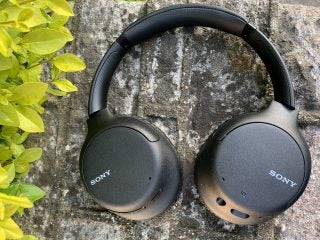 View from top of black Sony WH CH710N headphones resting on concrete floor, earcups back panel view