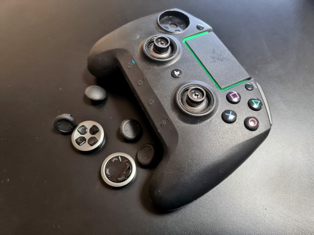 A black Razer Raiju gaming controller kept on a table with it's buttons cover removed
