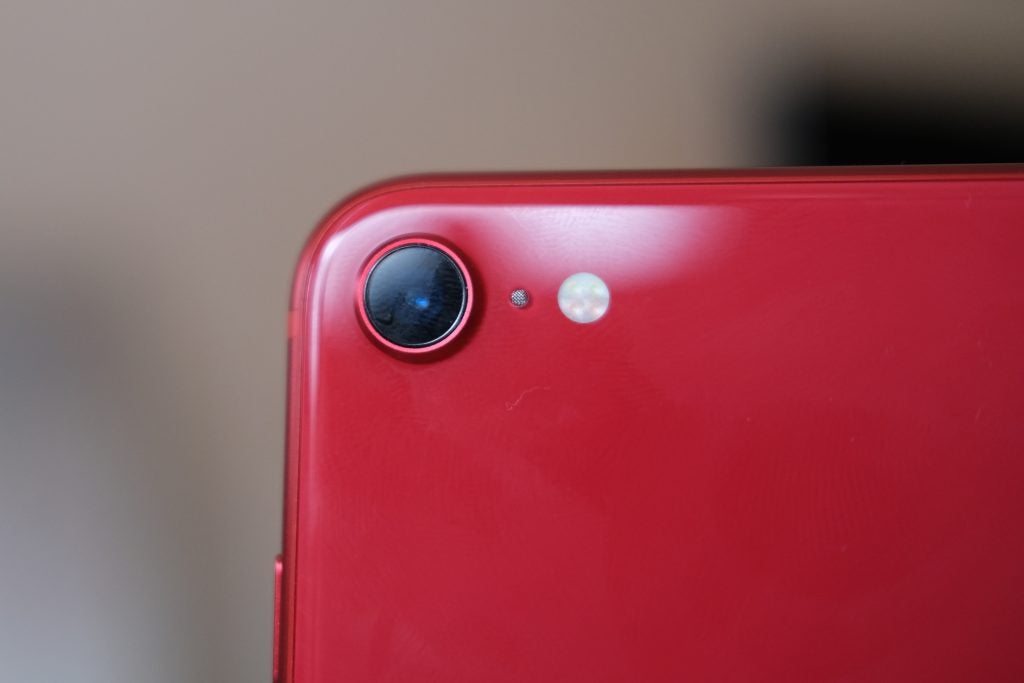 Close-up image of the rear camera of the red iPhone SE