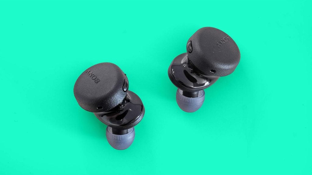 Sony WF-XB700Close up image of black Sony WF-XB700 earbuds resting on green background