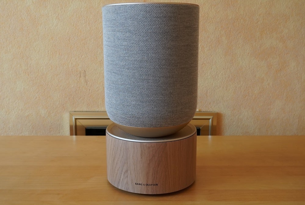 A silver Beosound balance speaker standing on a wooden table