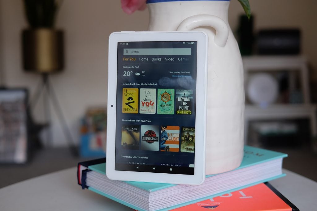 A white Amazon Kindle standing on books displaying store's homescreen