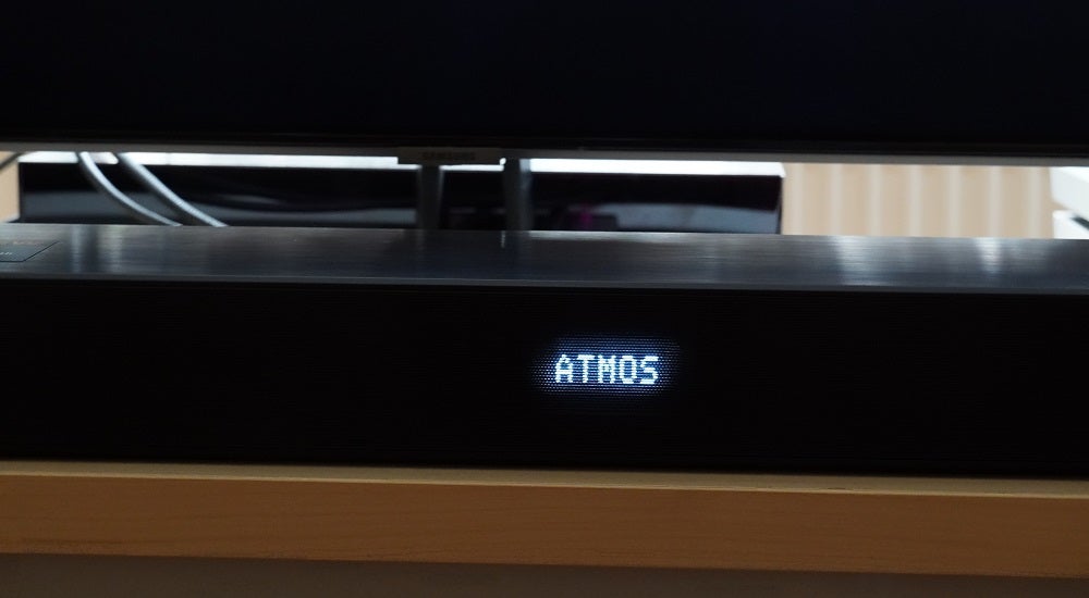 LG SN7CYA black LG SN7CY soundbar resting on a table displaying ATMOS on front panel