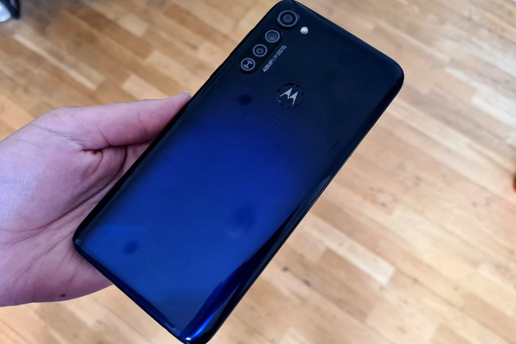 A blue Motorola G Pro held upside down in hand, back panel view with four cameras and Motorola logo