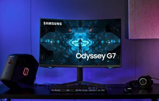 A black Odyssey G7 monitor standing on a table with necessary peripherals around