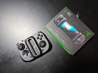 A black Razer Kishi gaming controller resting on a table with its box standing beside