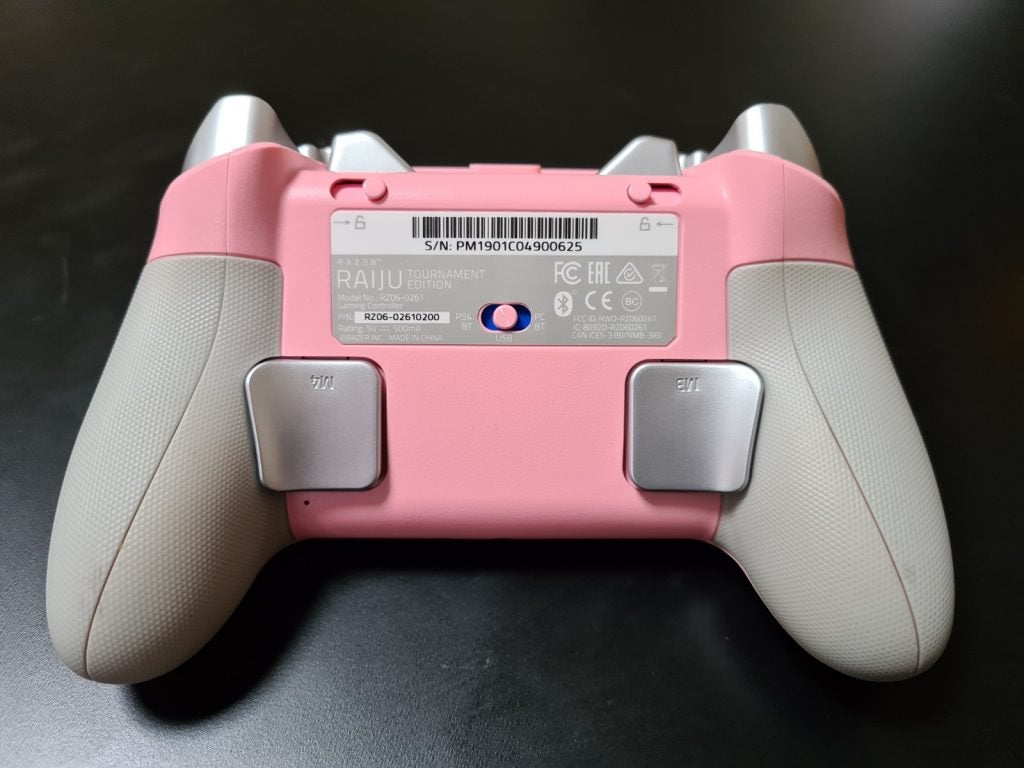Back panel view of a pink Razer Raiju tournamet gaming controller resting on a black table