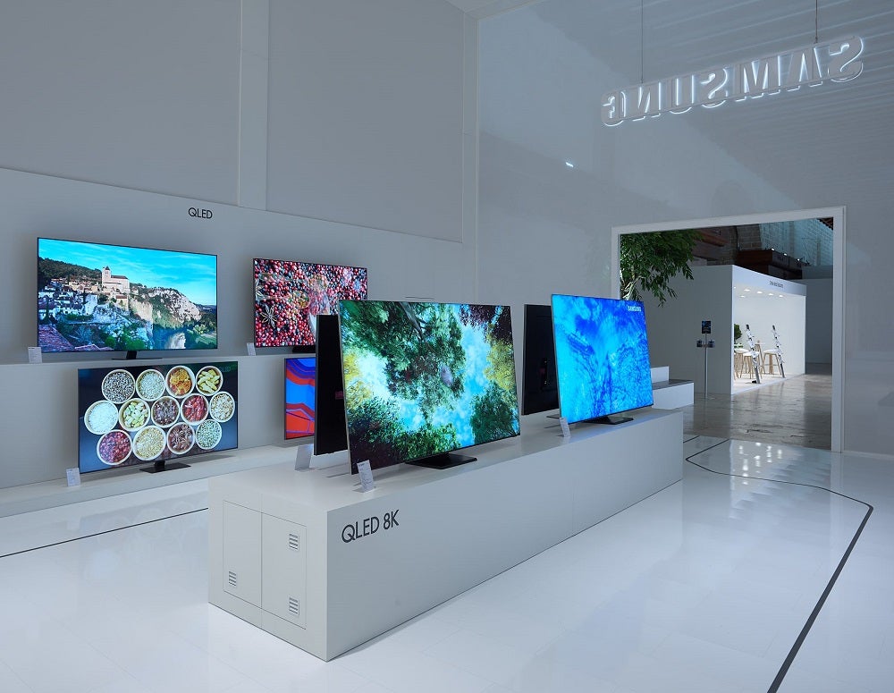 A number of TVs on display in a white Samsung QLED store