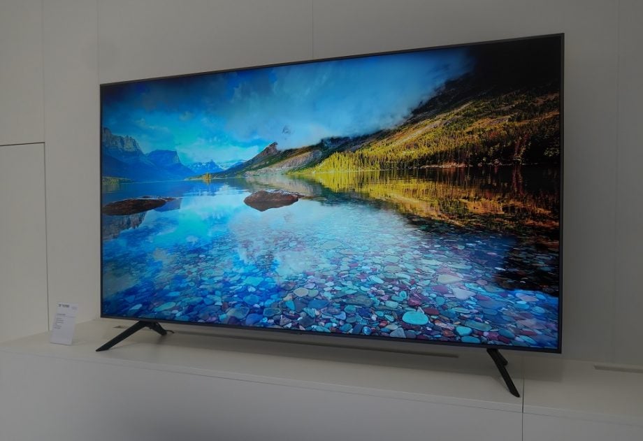 A black Samsung TU7100 TV standing on a table displaying a scenery