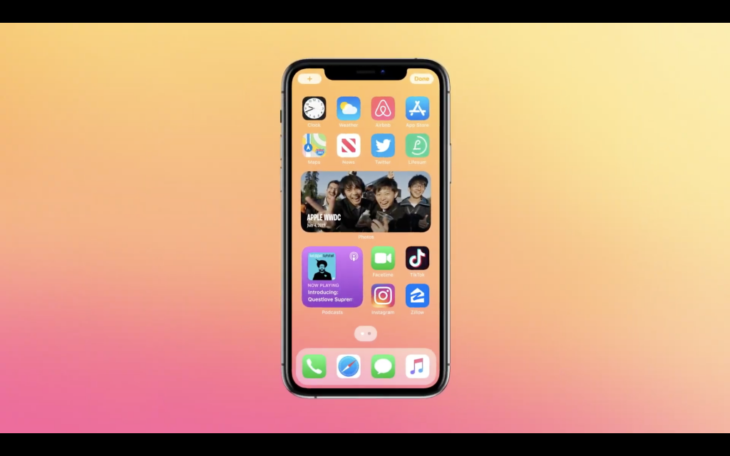 A black iPhone standing on colorful background displaying photos widget on homescreen