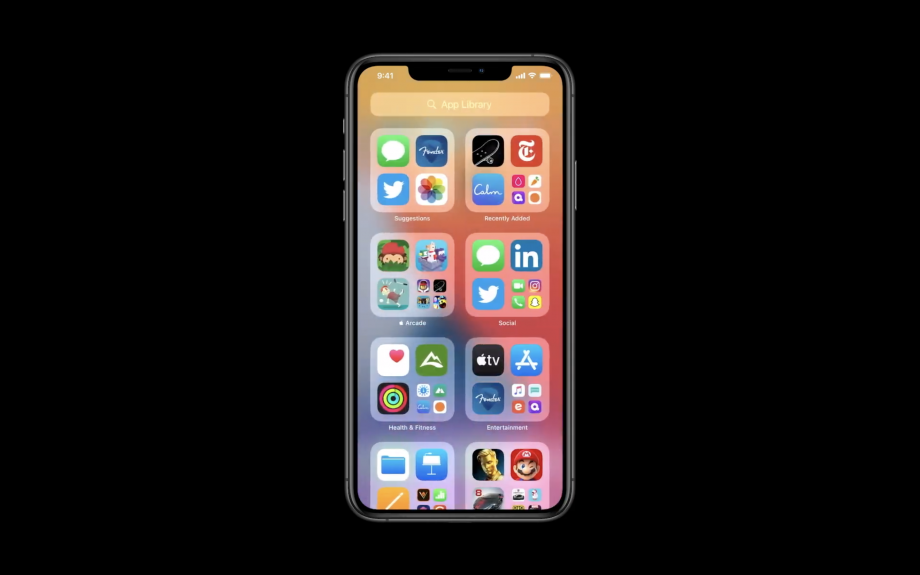 A black iPhone standing on black background displaying app library