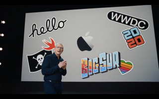 Tim Cook standing on a stage with stickers and emojis displayed on a screen behind him