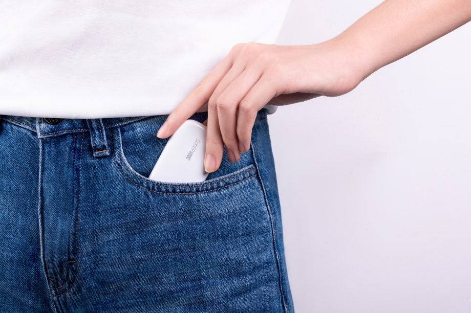 A girl putting a white Oppo 50W SuperVOOC charger in her blue jeans pocket