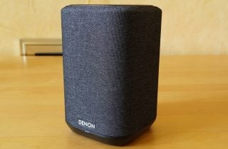 A black Denon Home 150 speaker standing on a table