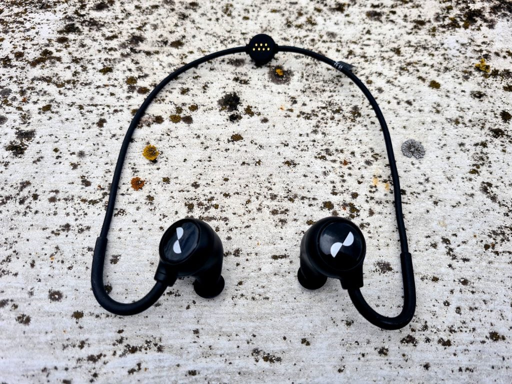 NuraLoopView from top of black Nuraloops wireless earphones resting on a concrete floor