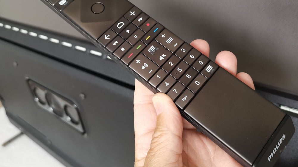 Close up image of a black Philips OLED805's remote held in hand