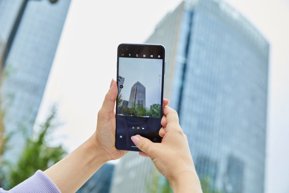 A smartphone held in hand displaying picture of a big buidling through camera app