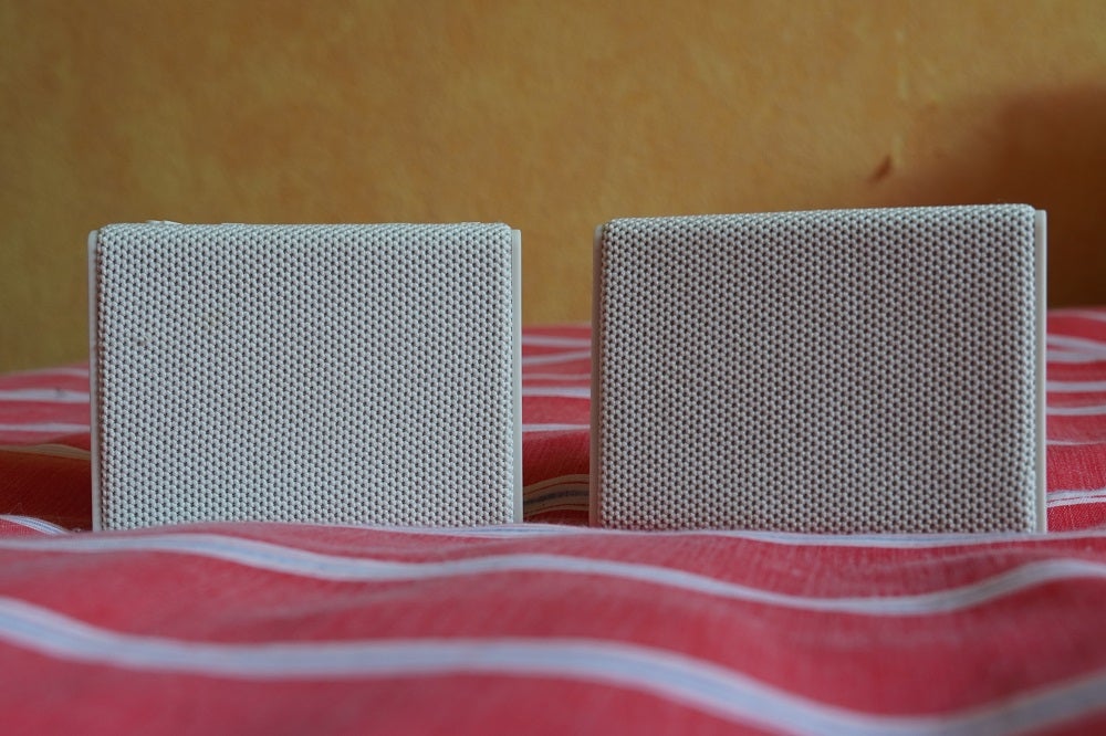 Two white Urbanista Sydeny speakers standing on bed